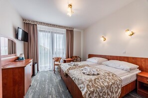 A hotel room with a bed, a desk, a chair, a television, and a window with curtains. - Studio for 2 people, Rewal (Rewal)