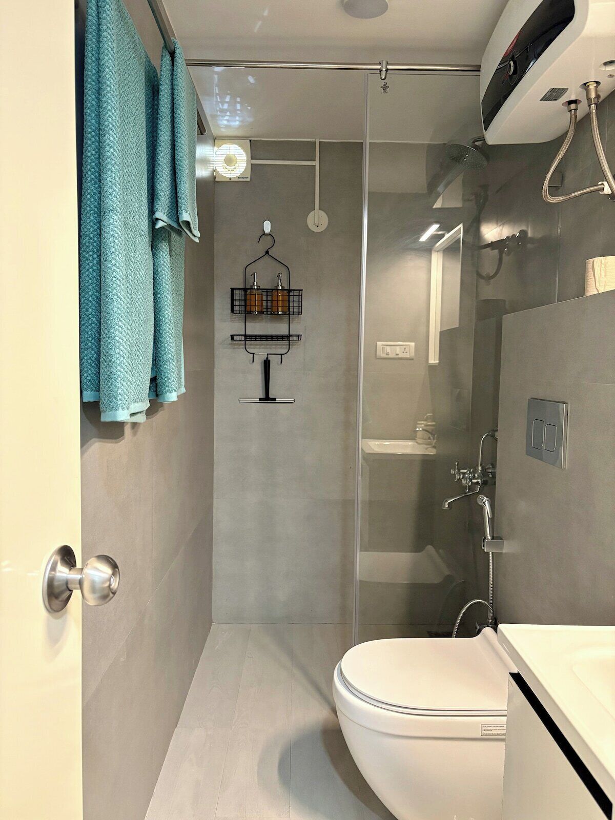 A modern bathroom with a glass-enclosed shower, a toilet, and a sink.
