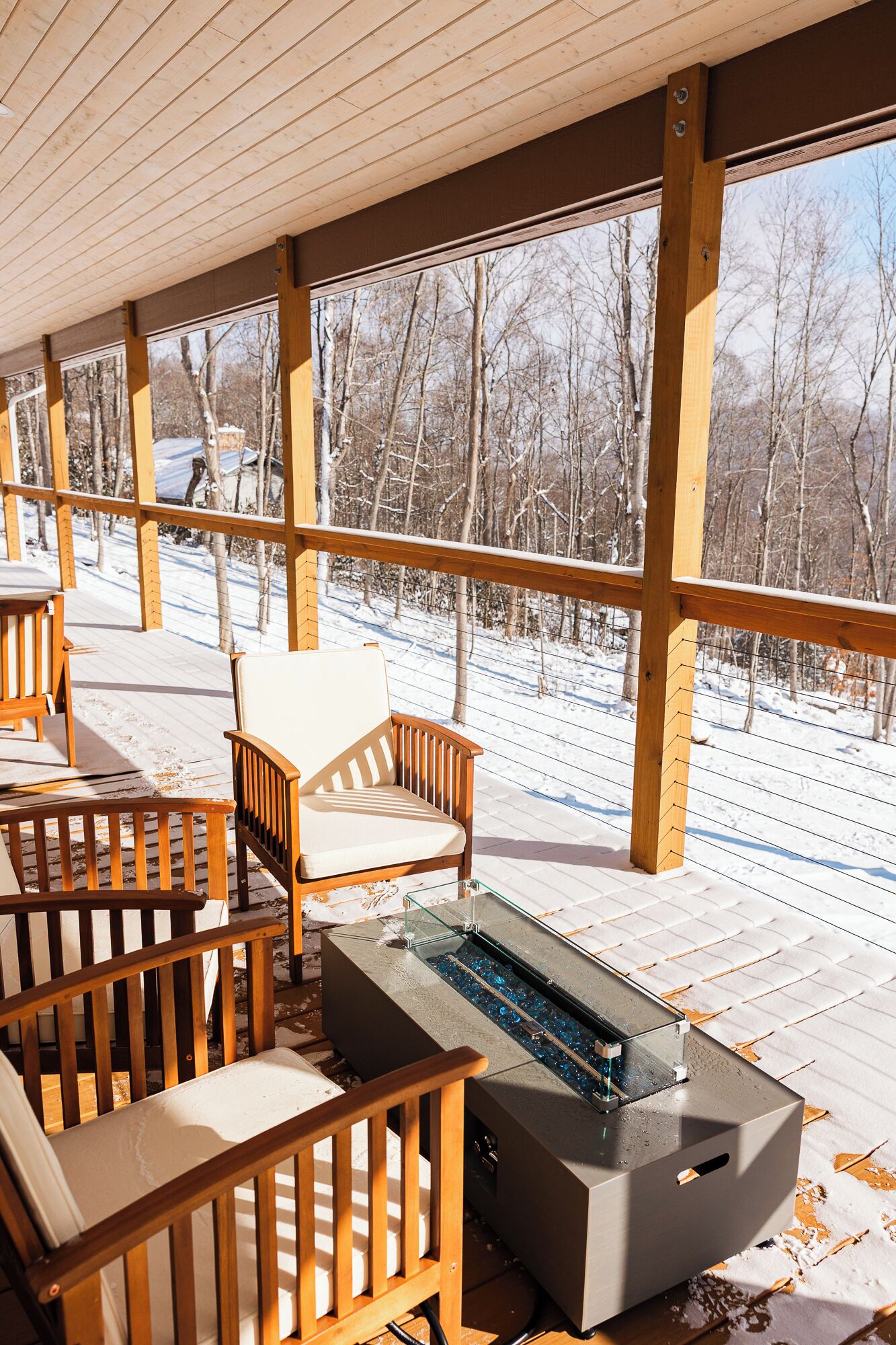 A covered outdoor seating area with wooden furniture and a glass-top table.