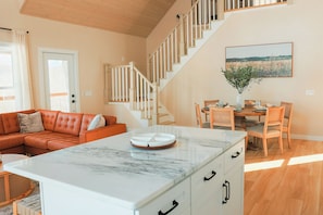 Un intérieur moderne comprenant un escalier, un coin repas et un espace de vie avec un canapé et une table basse.