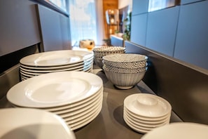A kitchen counter with stacks of white plates and bowls, some with patterns.