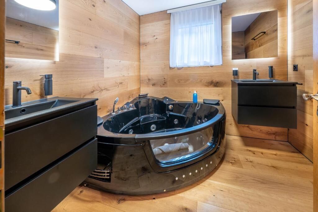 Ein modernes Badezimmer mit Holzvertäfelung, einer schwarzen Badewanne und einem eingebauten Waschbecken.