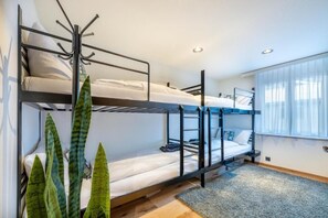 A bunk bed room with a coat rack, a window with curtains, and a plant. - Alpine Black Pearl - InspiringPlaces (Zermatt)