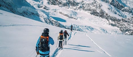 Un sentier de montagne enneigé, avec des skieurs.
