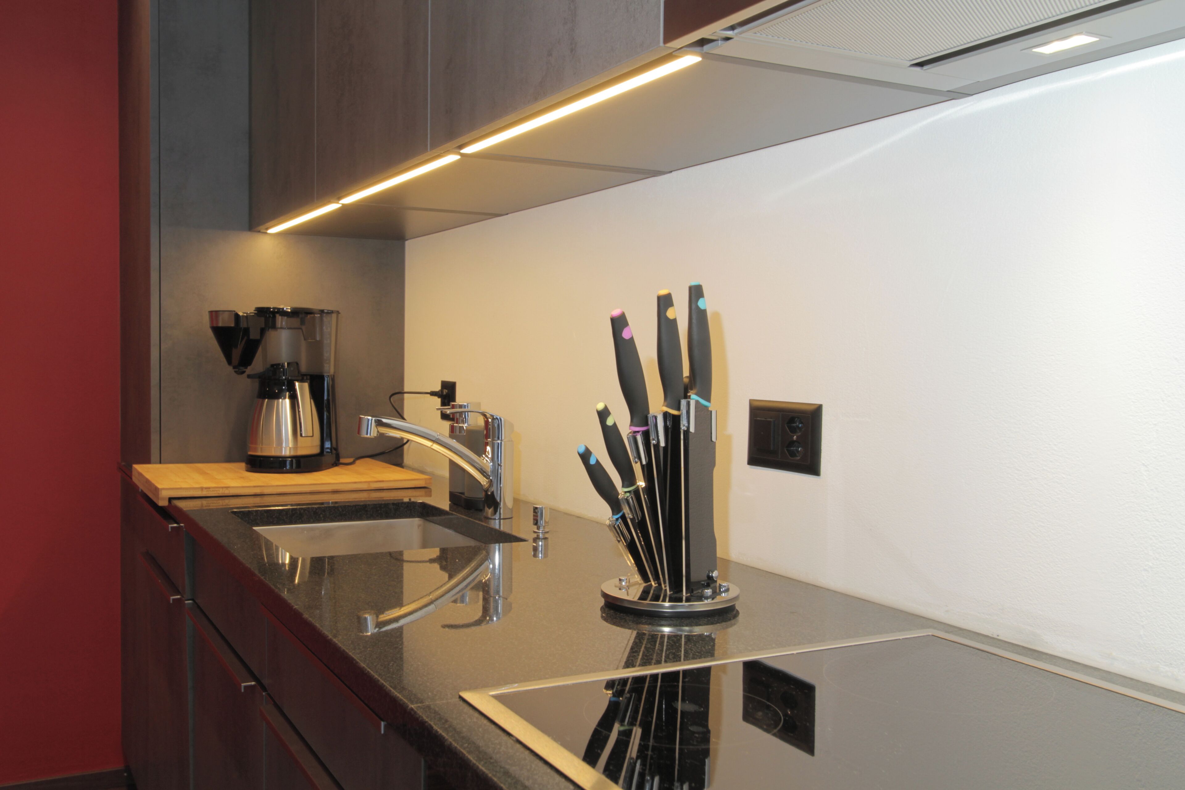 Una cocina moderna con electrodomésticos de acero inoxidable, cafetera y bloque de cuchillos.
