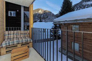 A wooden cabin with a balcony, a plaid cushion, and a view of snowy mountains. - Hoodoo panorama apartment ,House Mojo Zermatt (Zermatt)