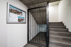 A staircase with a metal gate, a framed map on the wall, and a concrete ceiling. - Hoodoo panorama apartment ,House Mojo Zermatt (Zermatt)