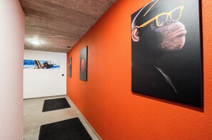 A hallway with artwork on the walls, a wooden ceiling, and black mats on the floor. - Hoodoo panorama apartment ,House Mojo Zermatt (Zermatt)