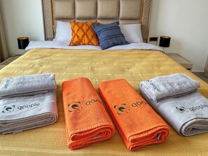 A neatly made bed with a beige headboard, white and blue pillows, and a yellow bedspread. There are two black lamps on either side of the bed. - Qoople Excellence B17 - Cozy 1-bedroom apartment in Alanya (Alanya)