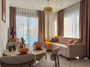 A modern living room with a dining area, a sofa set, and a chandelier. - Qoople Excellence B17 - Cozy 1-bedroom apartment in Alanya (Alanya)