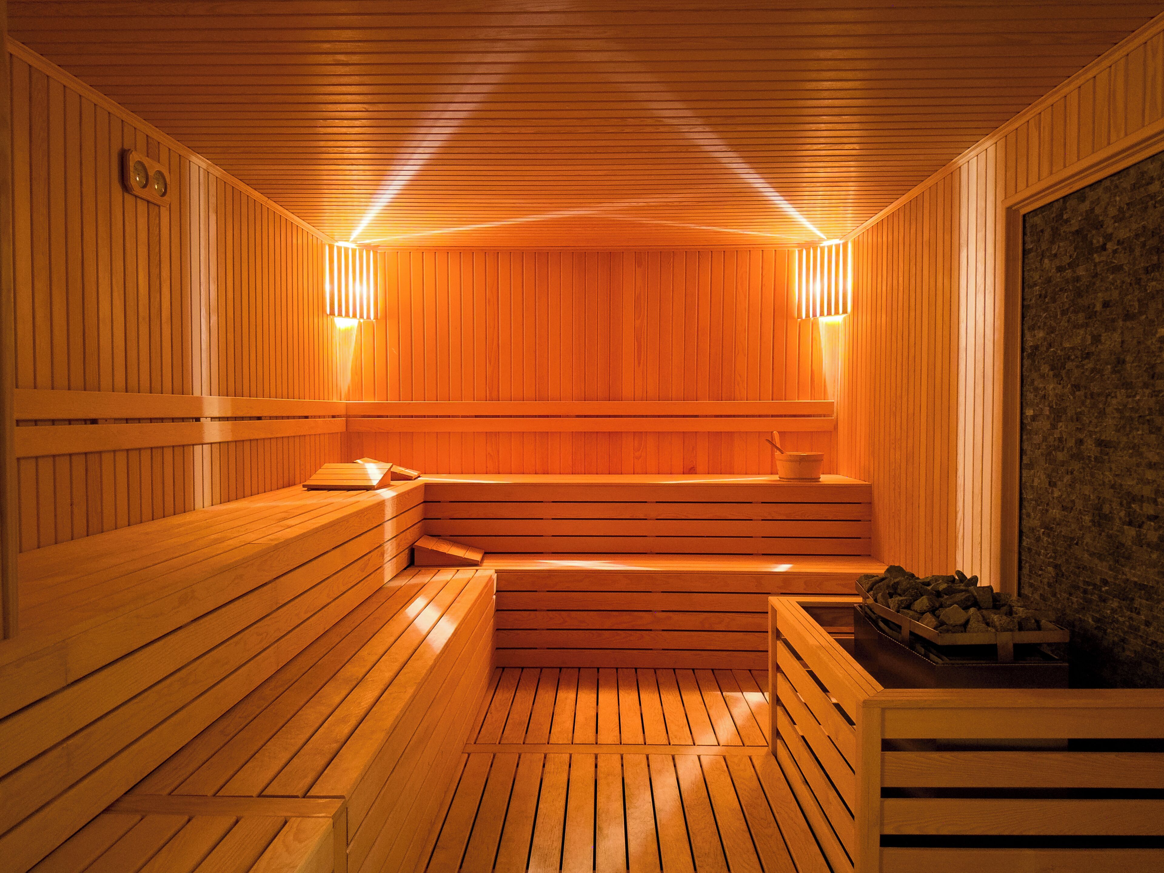 Uma sauna com bancos de madeira, parede de pedra e lareira.