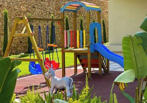Ein Spielplatz mit Rutsche, Schaukeln und einer Kletterkonstruktion.