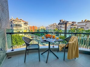 A balcony with a table, chairs, and a view of a cityscape. - Qoople Excellence B17 - Cozy 1-bedroom apartment in Alanya (Alanya)