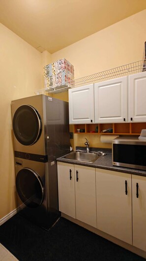 A compact kitchen with a built-in washer and dryer, a microwave, and a sink.
