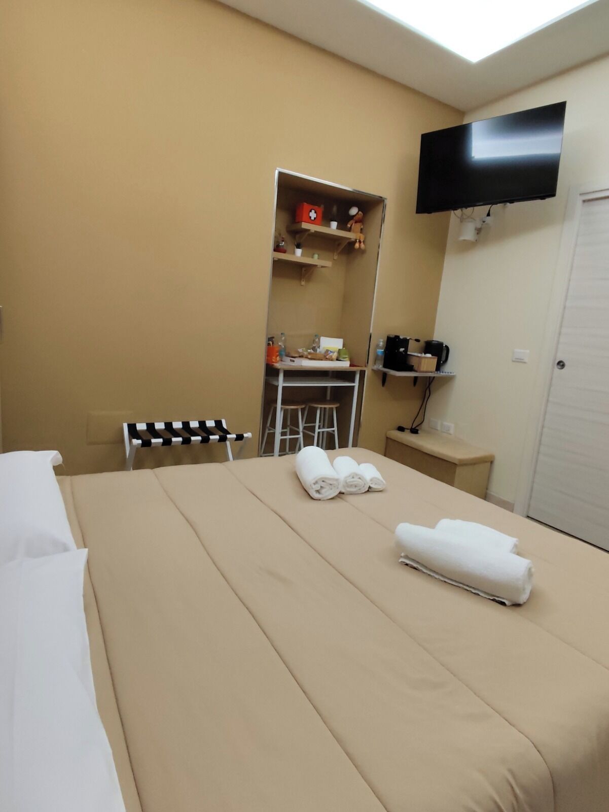 A hotel room with a bed, a desk, a chair, a TV, and a wardrobe.