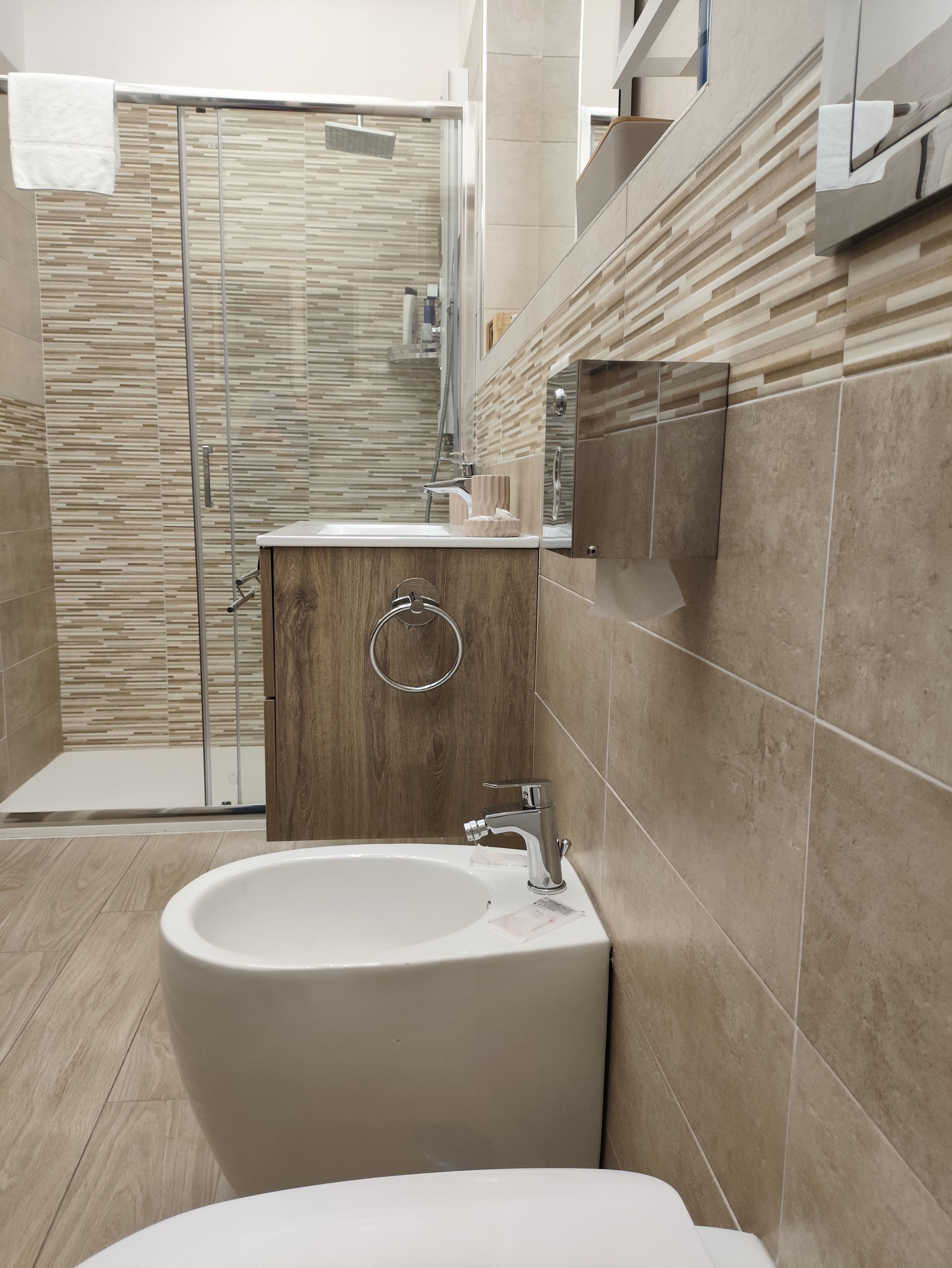 A modern bathroom with a freestanding bathtub, a glass shower enclosure, and a wooden vanity.