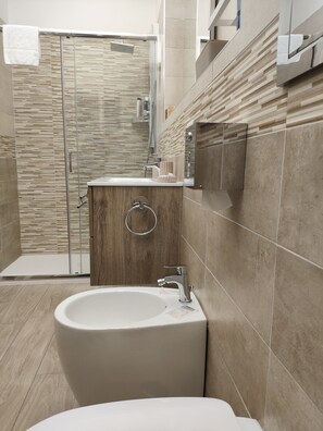 Un baño moderno con una bañera independiente, cabina de ducha con mampara de vidrio y tocador de madera.