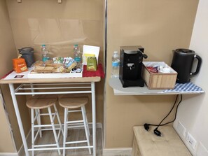 Una kitchenette equipada con cafetera, hervidor de agua, pan y una botella de agua.