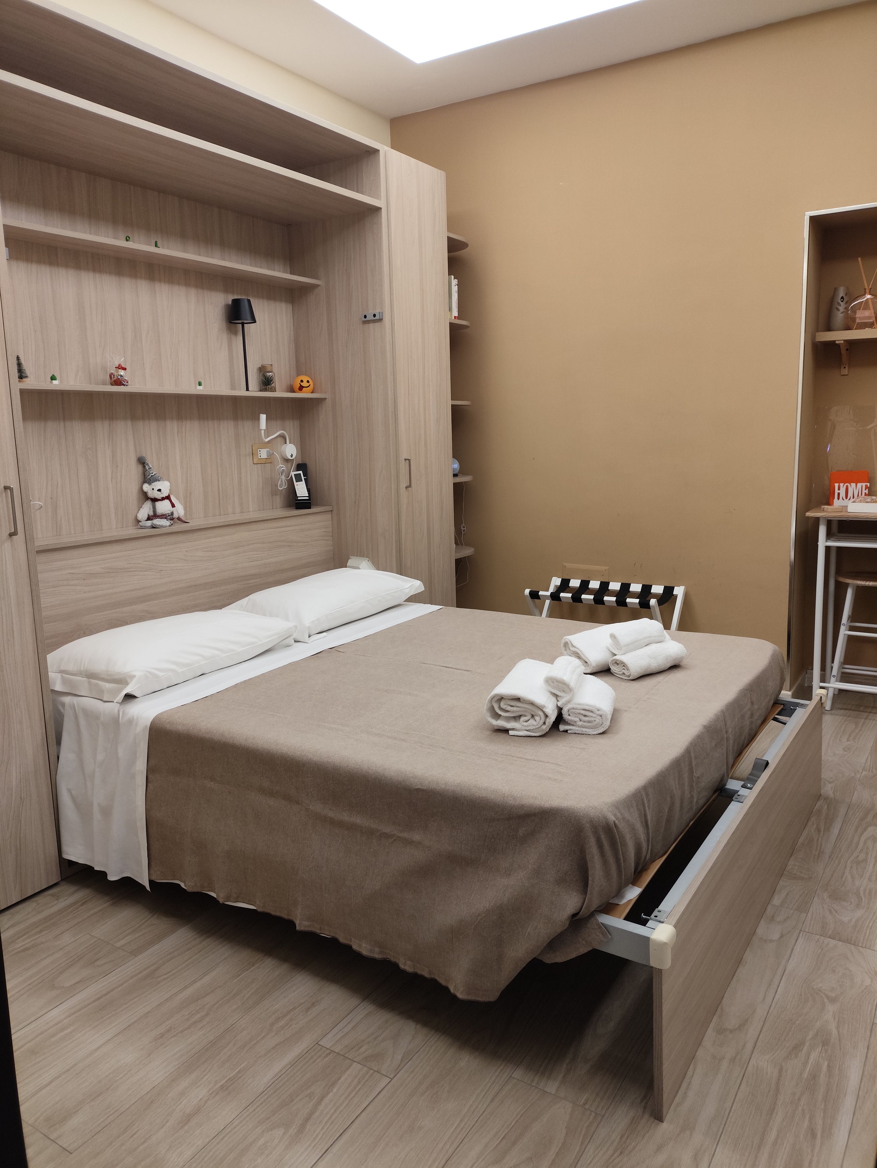 A hotel room with a bed, a wardrobe, and a desk area.