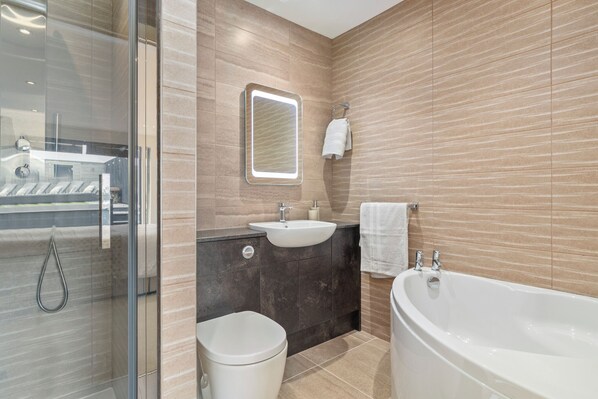 Un bagno moderno con cabina doccia in vetro, lavandino, WC e vasca da bagno.