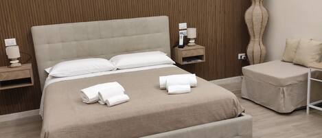 A neatly made bed with a headboard, a bedside table with a lamp, and a wall-mounted artwork.