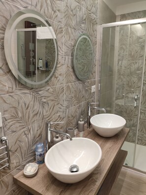 Un bagno con due lavandini, uno specchio e una doccia.