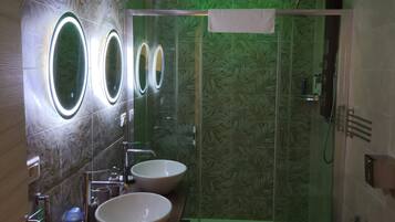 A modern bathroom with two sinks, a glass shower enclosure, and a toilet.