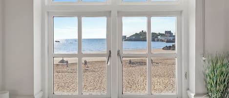 A bay window with a view of a beach and a castle.