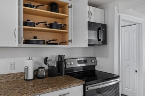 A kitchen with white cabinets, a stainless steel stove, a microwave, and a coffee maker.