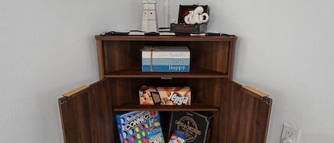 Una estantería de madera con varios juegos de mesa y una pequeña figurita blanca.