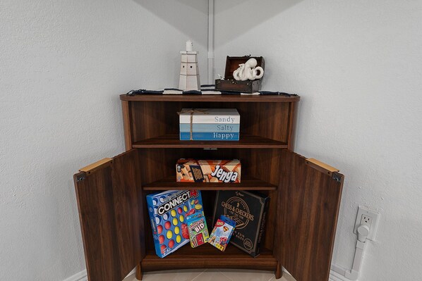 A wooden bookshelf with various board games and a small white figurine.