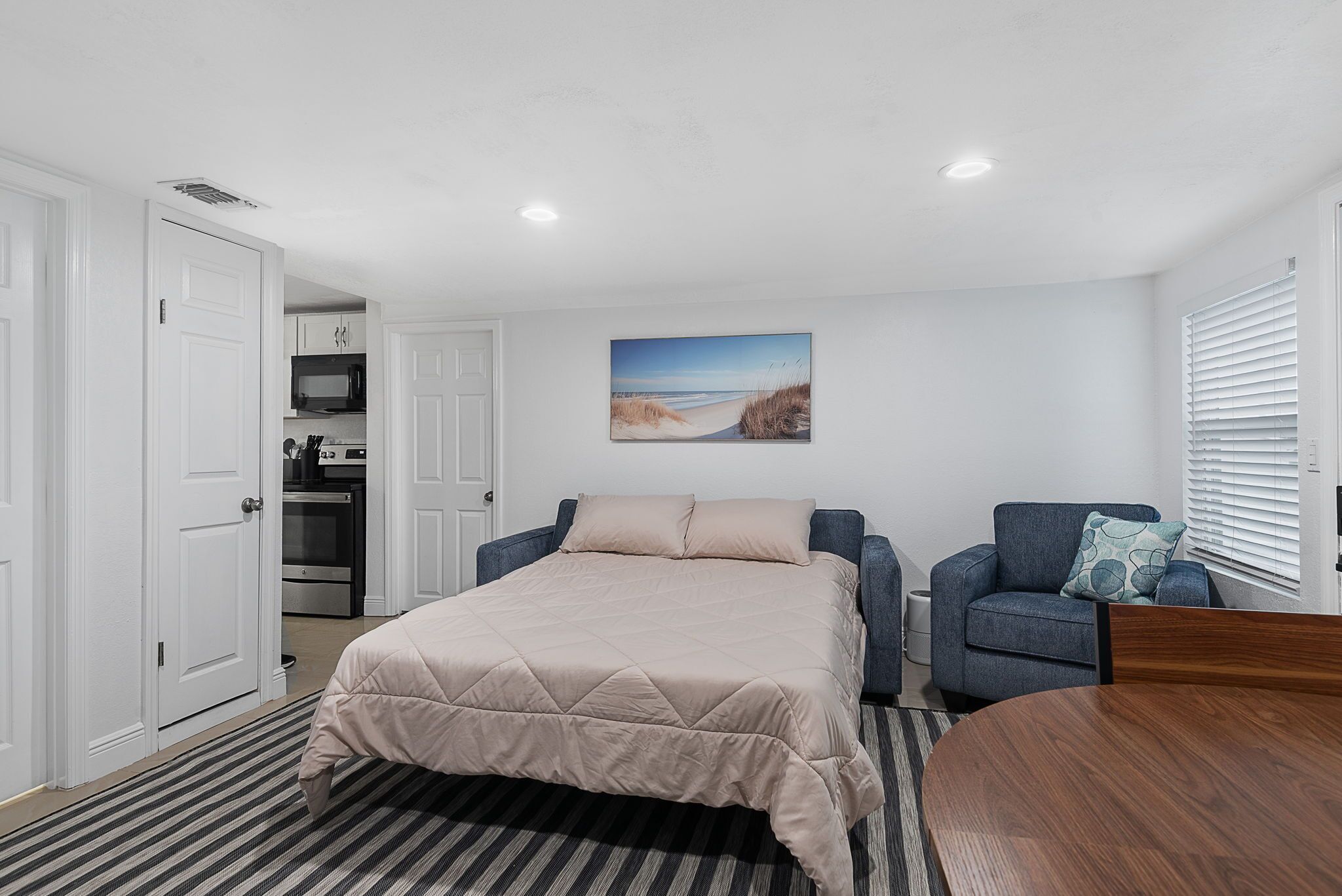 Un dormitorio con cama, sofá, mesa de comedor y zona de cocina.