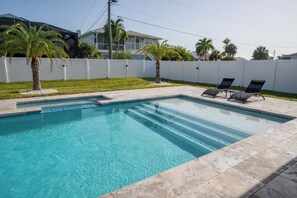 A rectangular swimming pool with clear blue water, surrounded by a white fence, and two lounge chairs on the right side. - Beach Escape, Private Pool ,Sleeps 8 (Fort Myers Beach)