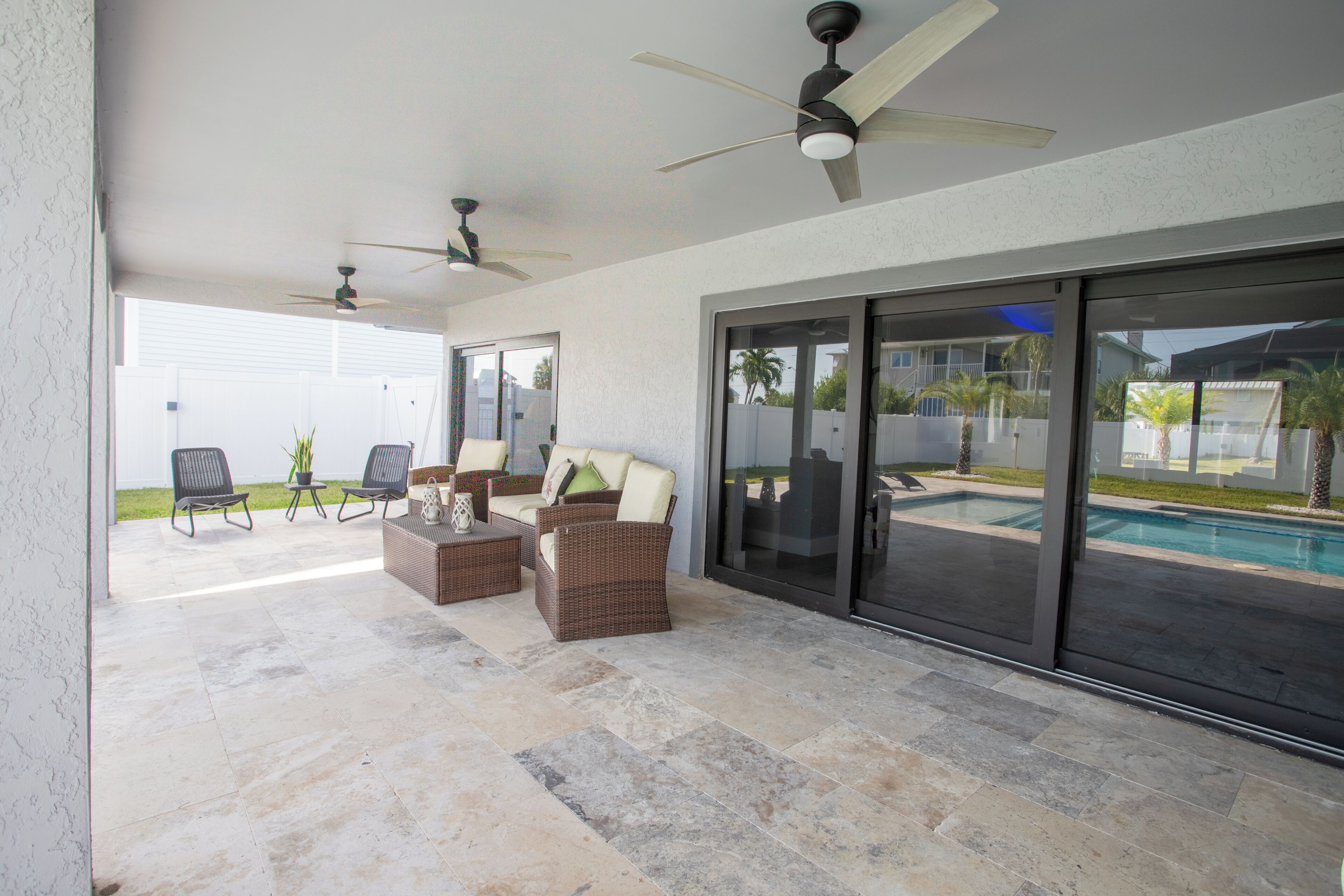 Un patio al aire libre con piscina, mobiliario y ventiladores de techo.
