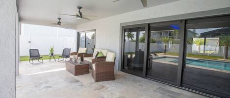 Un patio al aire libre con piscina, mobiliario y ventiladores de techo.