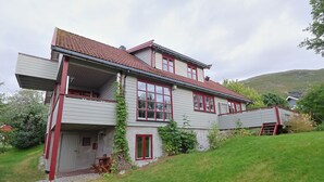 A two-story house with a balcony, a red door, and a red roof. - Aurora House – A Family & Friends Retreat in Tromsø (Tromsø)