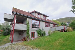 Ein zweistöckiges Haus mit Balkon, rotem Eingang und rotem Dach.