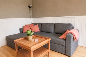 A grey sofa with a plant and two candles on a wooden side table. - Aurora House – A Family & Friends Retreat in Tromsø (Tromsø)