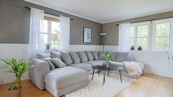 Ein modernes Wohnzimmer mit einem grauen Ecksofa, einem runden Couchtisch und einem weißen Teppich.