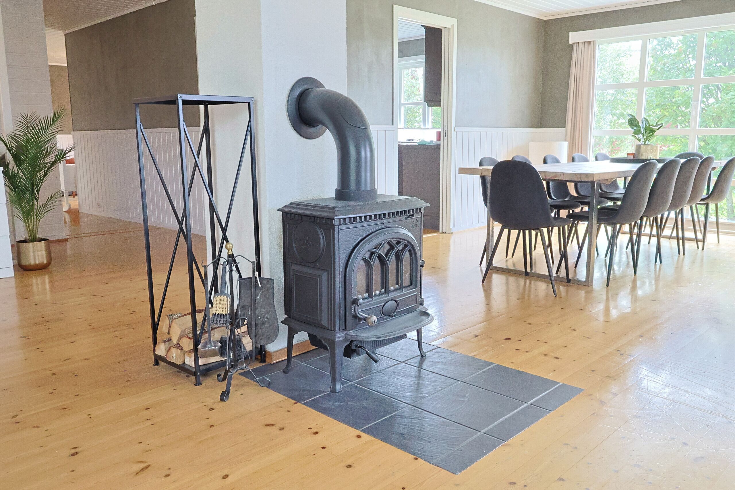 Une pièce avec un poêle à bois, une table à manger avec des chaises et une grande fenêtre.