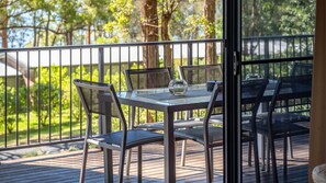 Eine Terrassengruppe mit Tisch und Stühlen, umgeben von einem Metallgeländer und Bäumen.