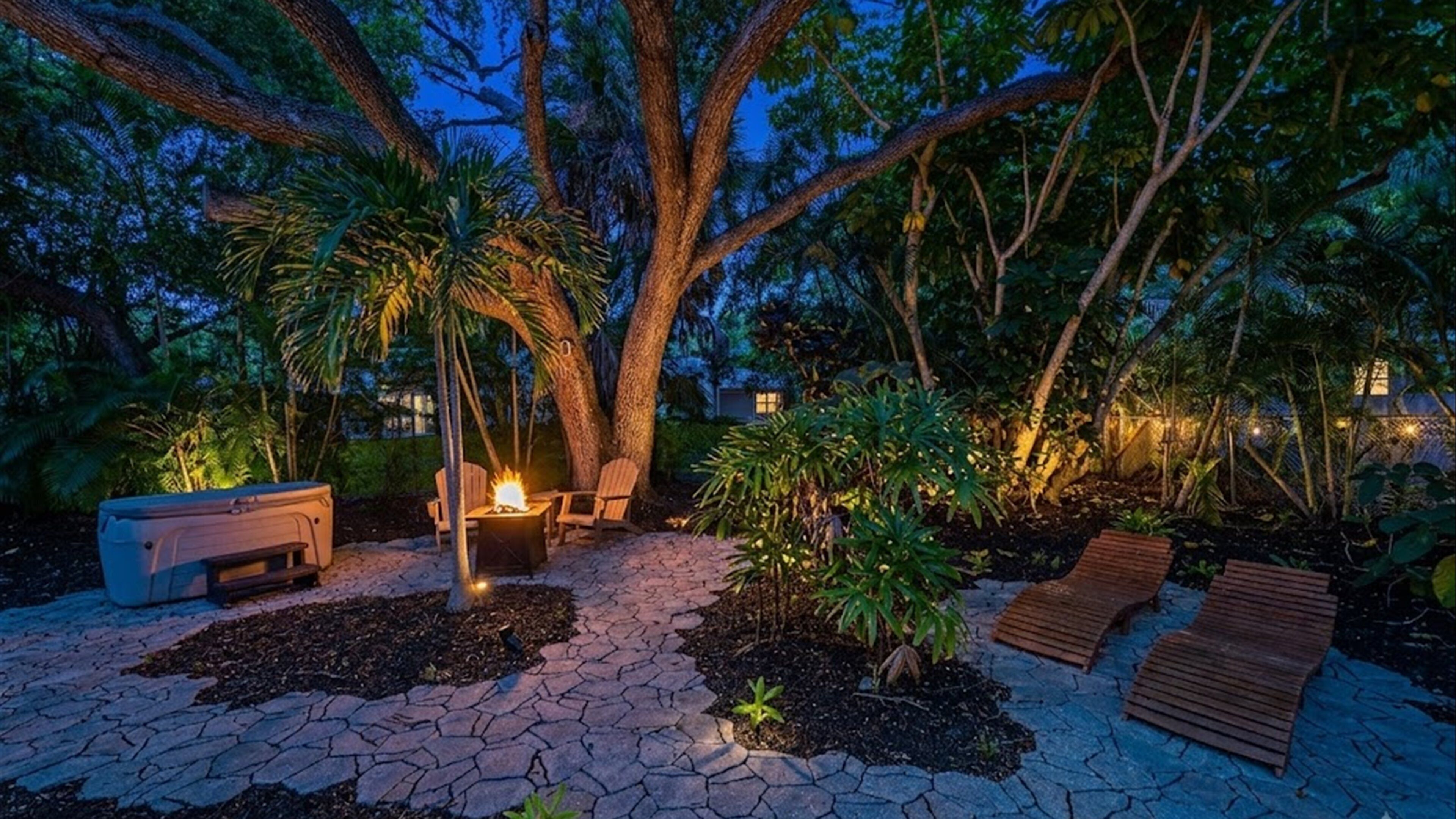An outdoor patio area with a fire feature, seating, and a paved walkway.