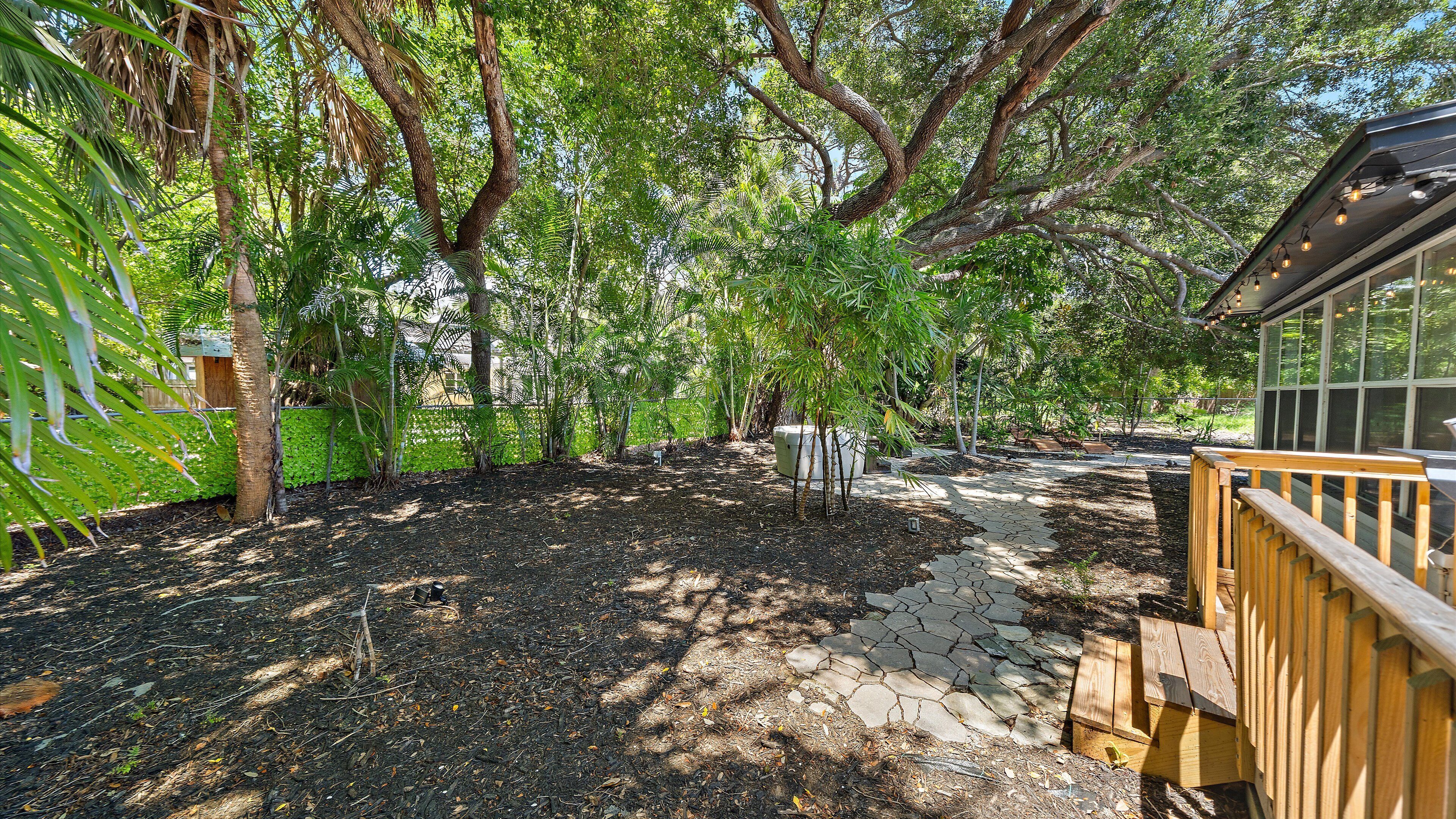 A garden with a stone pathway leading to a wooden deck.