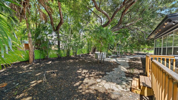 A garden with a stone pathway leading to a wooden deck. - Cozy Cottage Mins to Siesta Key & Downtown, Hot Tub (Sarasota)