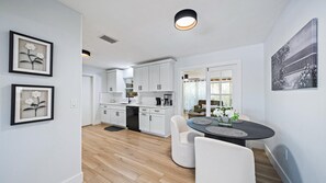 Gather around the sleek dining table in this bright, open kitchen where warm wood floors and modern fixtures create an inviting space for your morning coffee or evening meals together. - Cozy Cottage Mins to Siesta Key & Downtown, Hot Tub (Sarasota)