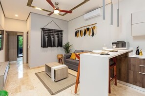 A modern kitchen with a microwave, a dining table, and a ceiling fan. - Private Jacuzzi · Infinity Pool · Tulum Beach Zone (Tulum Municipality)