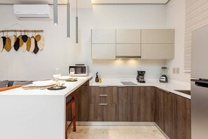 A modern kitchen with a central island, wooden cabinets, and a microwave. - Private Jacuzzi · Infinity Pool · Tulum Beach Zone (Tulum Municipality)