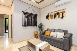 A modern living room with a grey sofa, a coffee table, and wall art. - Private Jacuzzi · Infinity Pool · Tulum Beach Zone (Tulum Municipality)