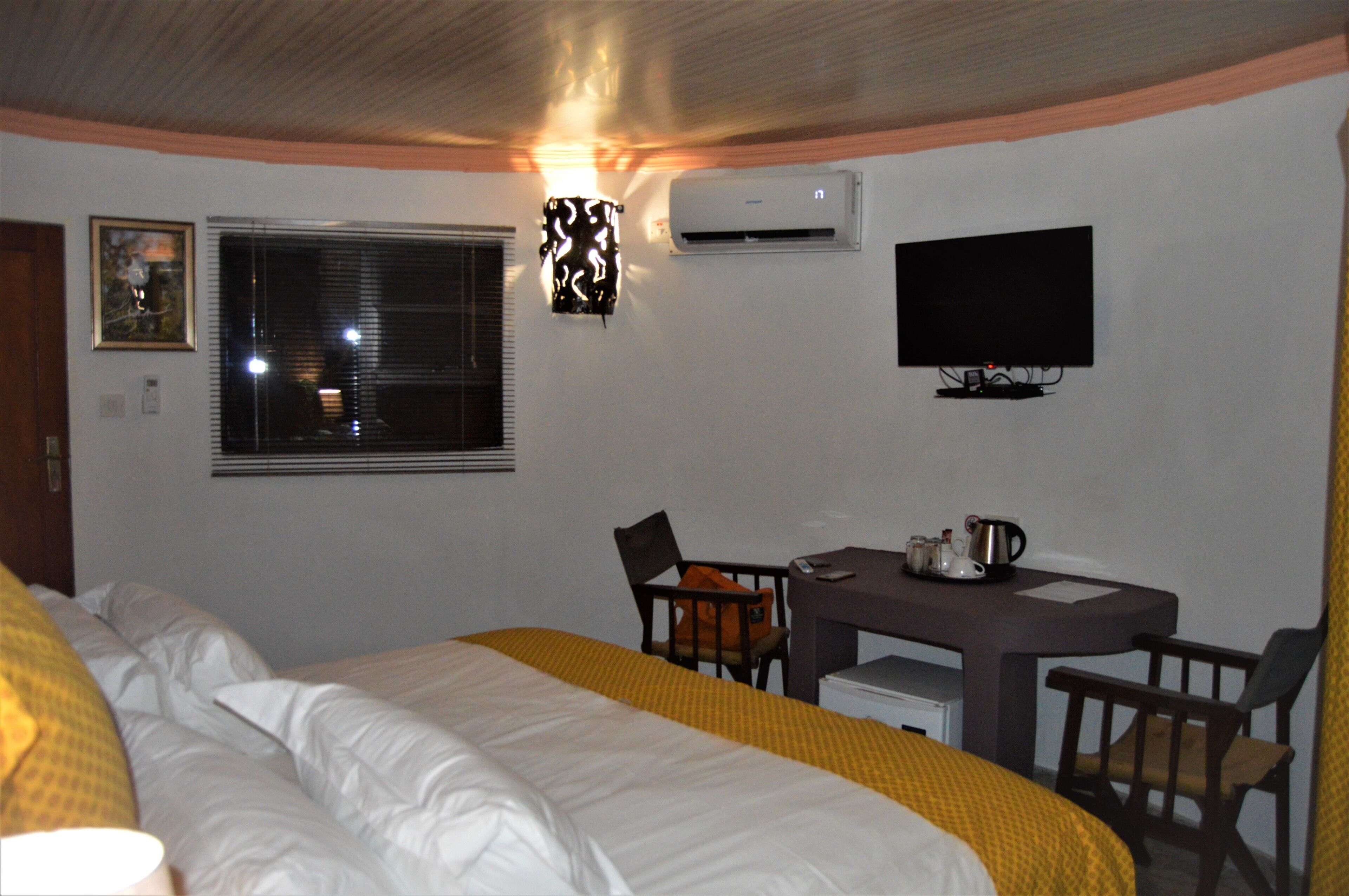 Habitación de hotel con cama, escritorio, silla, televisión y aire acondicionado.