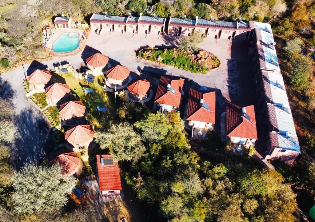 An aerial view of a resort with multiple buildings, a swimming pool, and a landscaped area.
